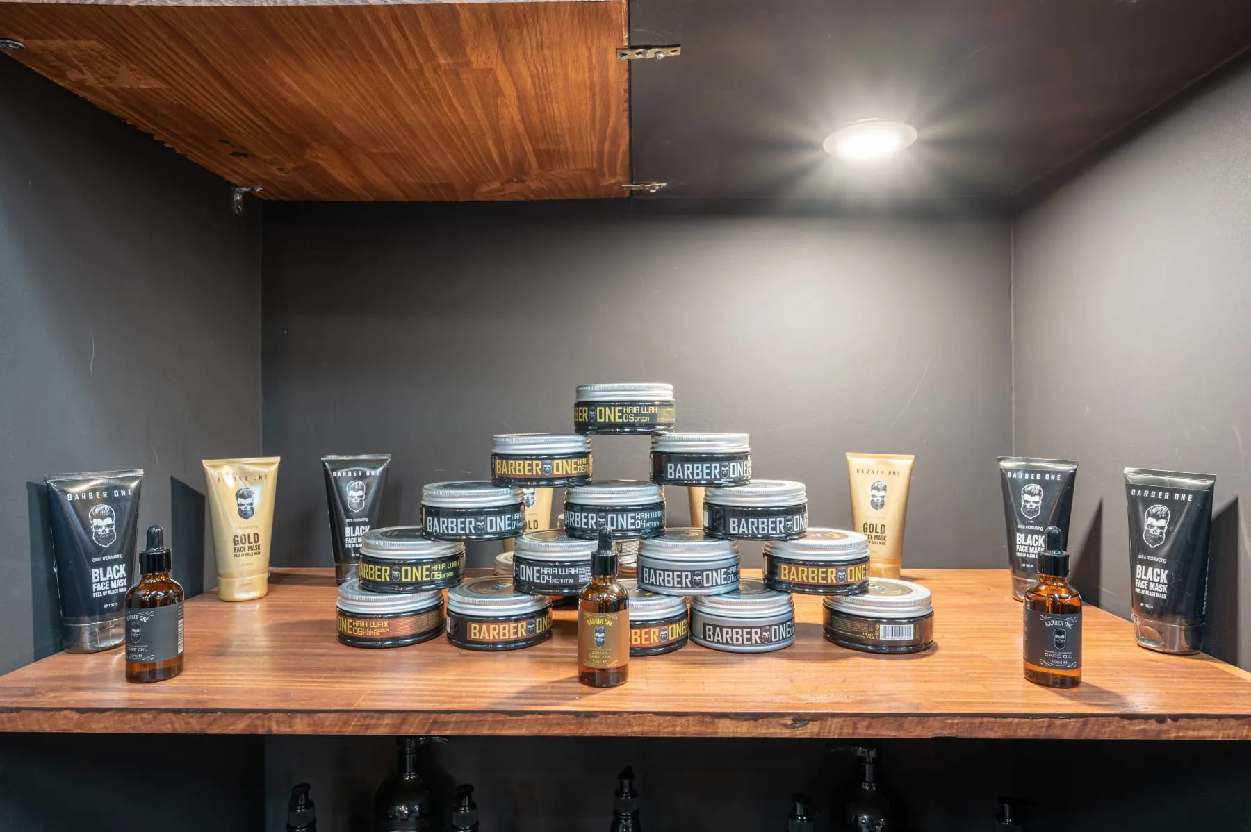 Les produits du salon Allure Barber alignés sur une étagère en bois.