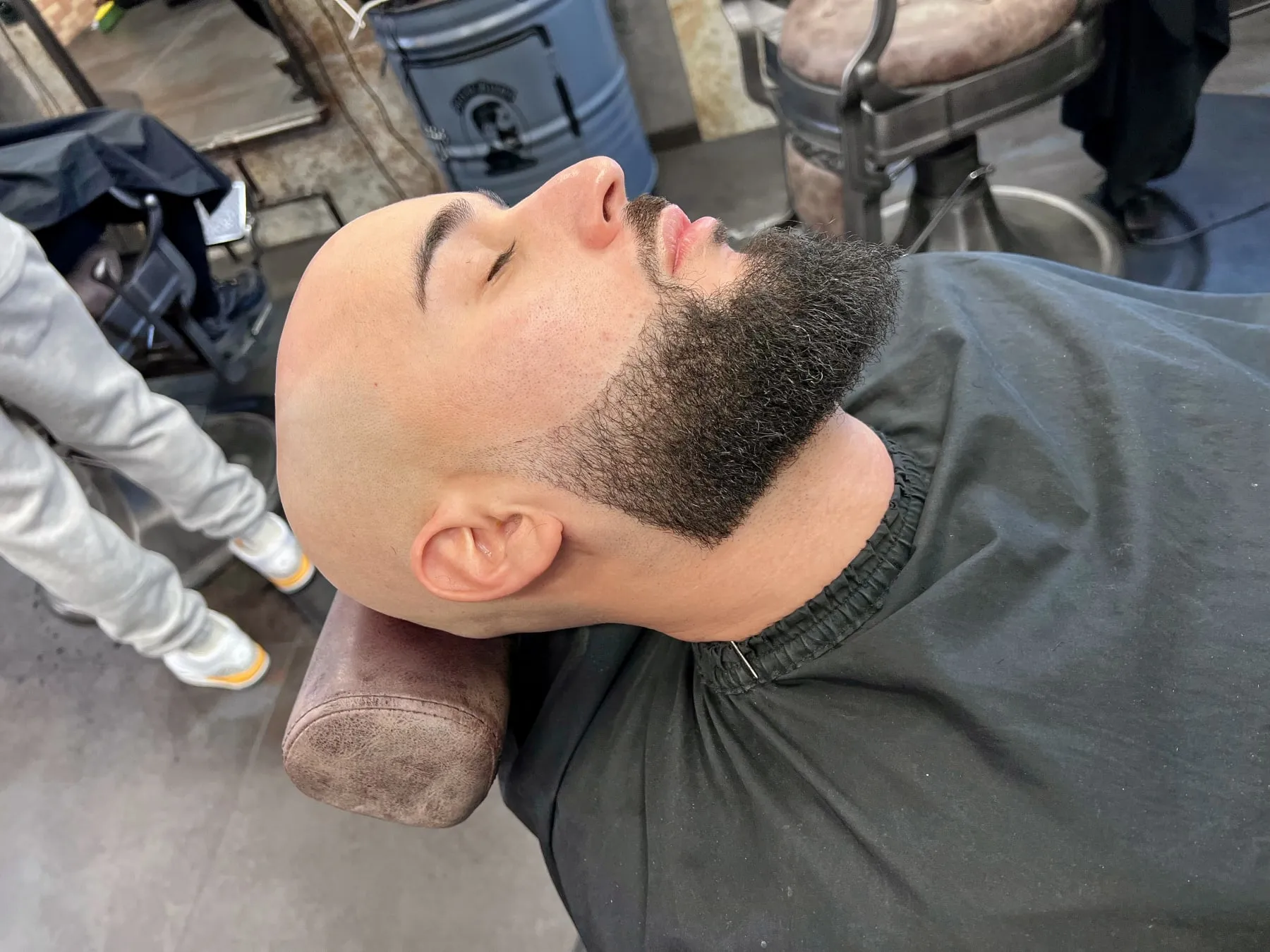 Serviette chaude pendant un soin du visage chez Allure Barber.
